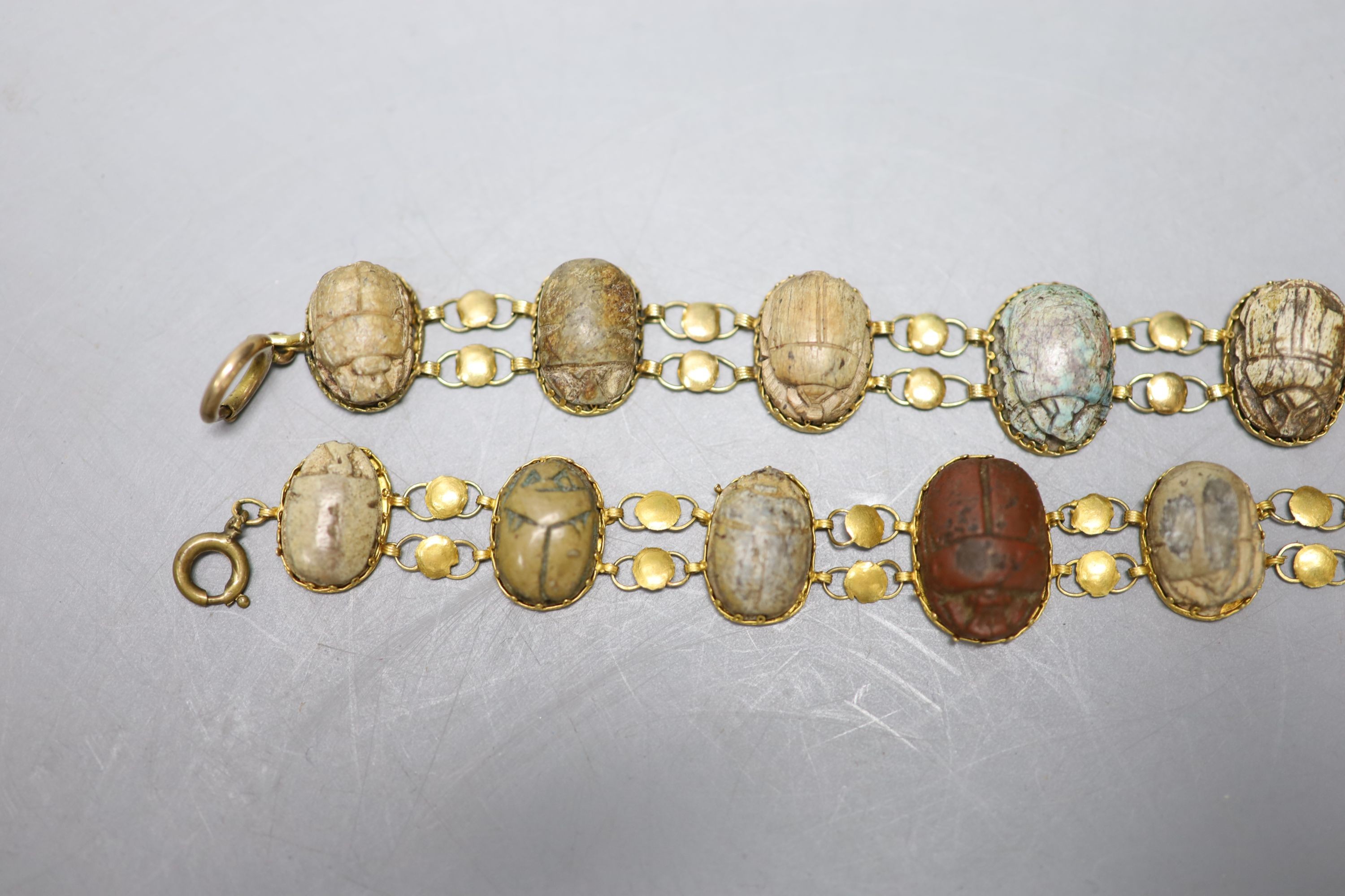 Two similar early 20th century yellow metal mounted scarab bracelets (a.f.), 18.5cm et infra, gross weight 38.1 grams.